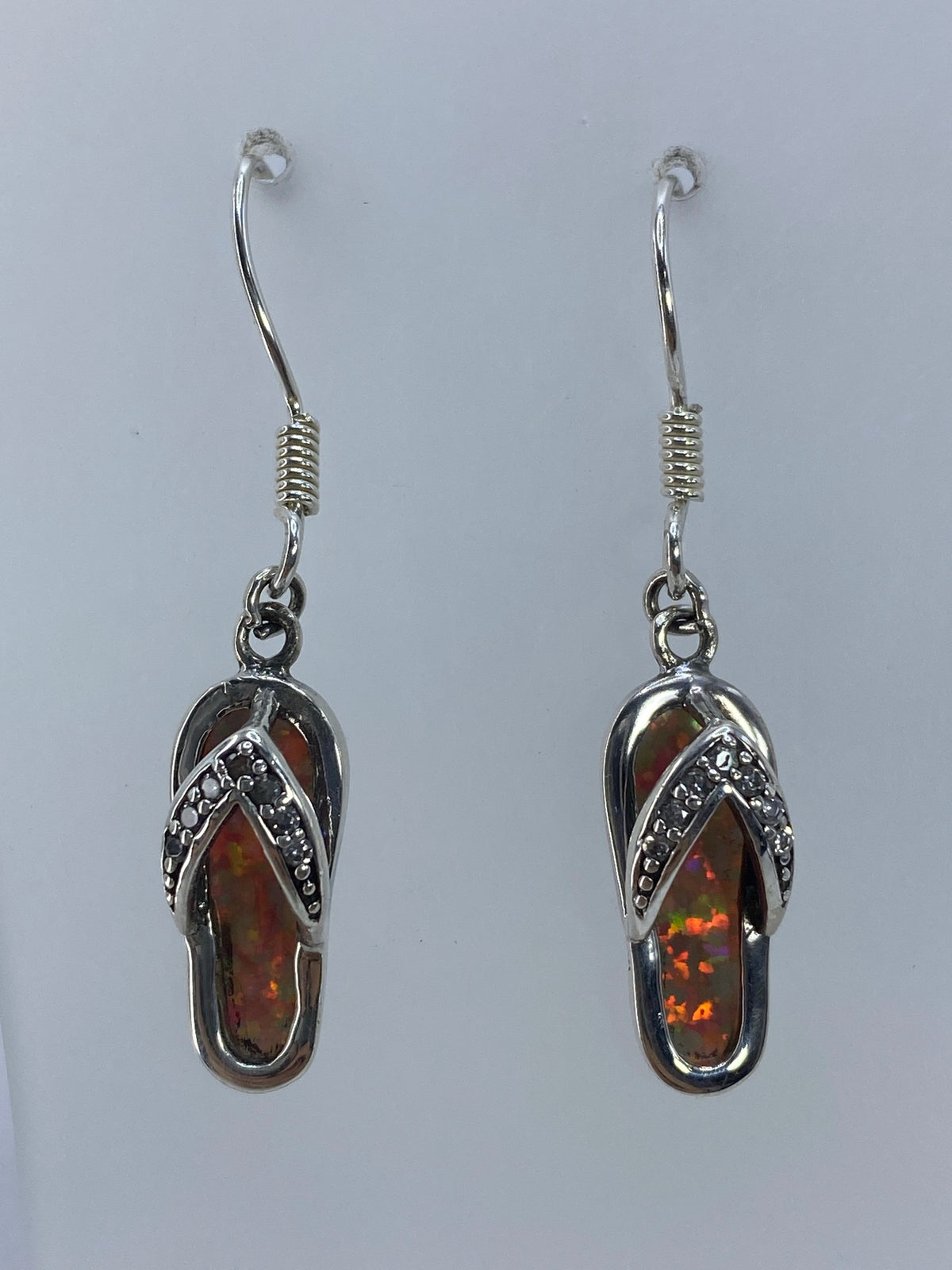 Aretes de ópalo de fuego en plata 925 mostrando los detalles en relieve y el brillo multicolor