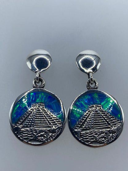 Aretes en la mano mostrando el relieve del Calendario Azteca