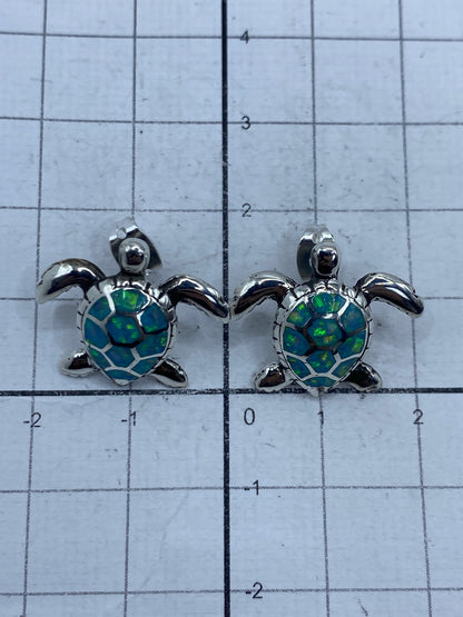 Aretes tortuga en escala, junto a regla de centímetros: 1.7 cm de largo × 2 cm de ancho