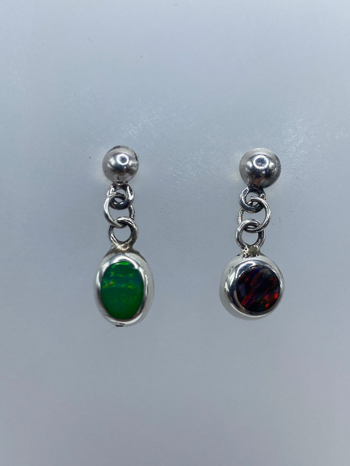 Par de aretes de plata con ópalo de fuego multicolor sobre fondo gris