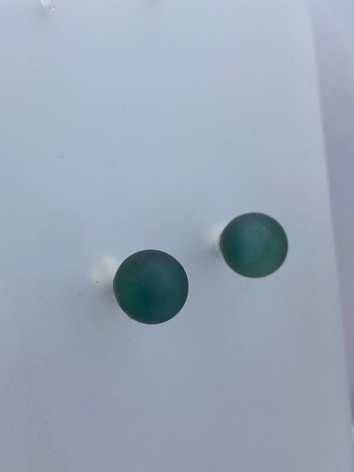 Aretes minimalistas en plata sobre escala de medición mostrando tamaño de 1.9 cm