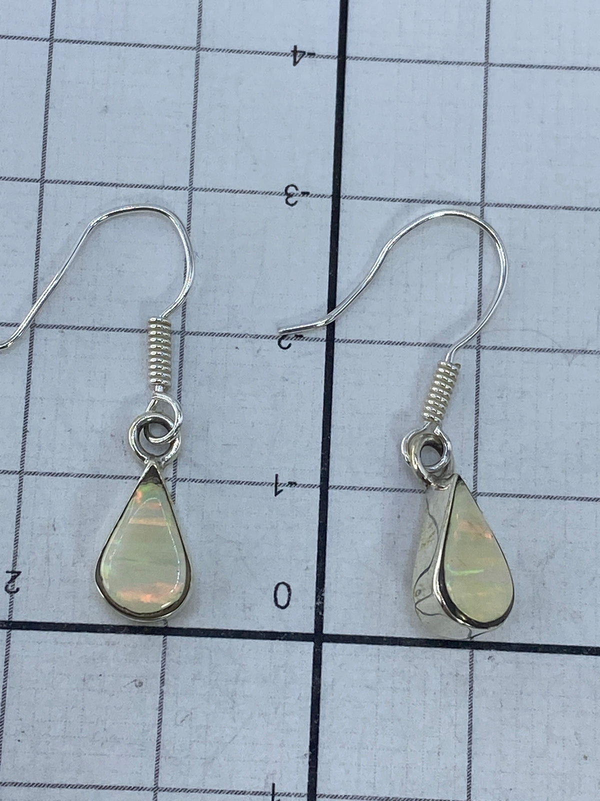 Aretes de plata 950 con opalo de fuego visto de frente, brillo multicolor