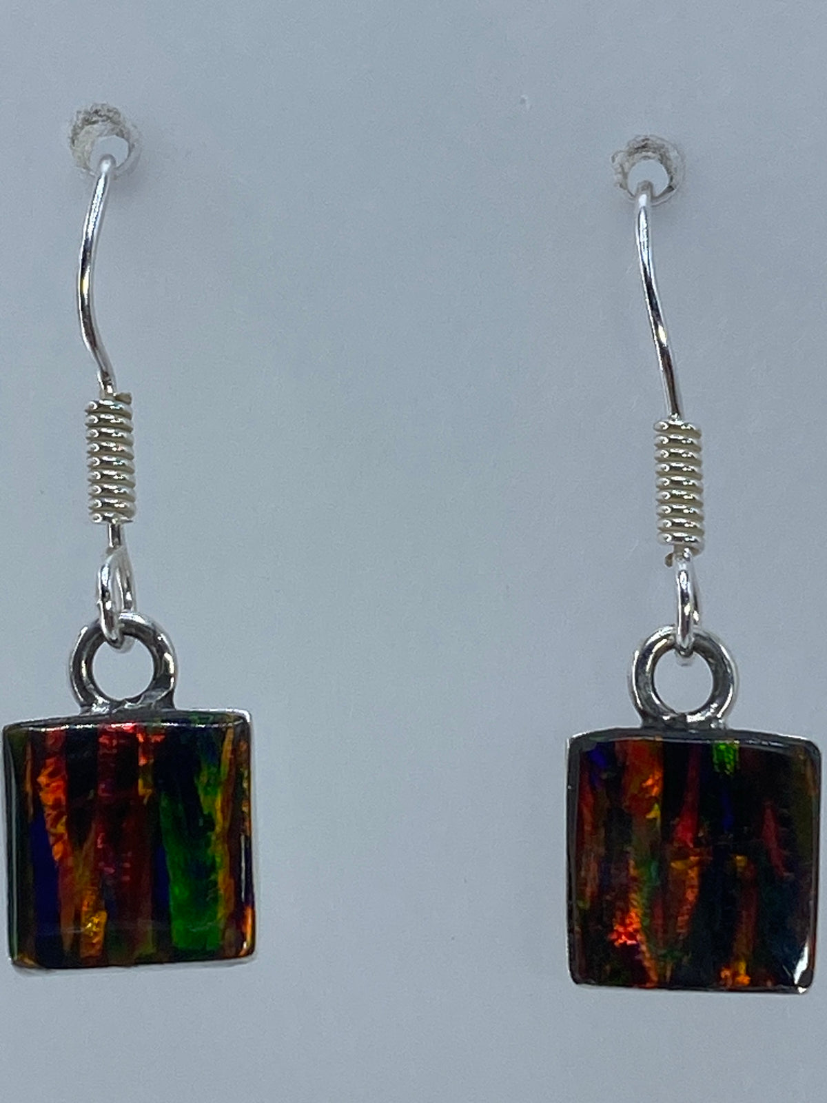 Aretes de ópalo de fuego multicolor sobre fondo neutro, largo 2.8 cm