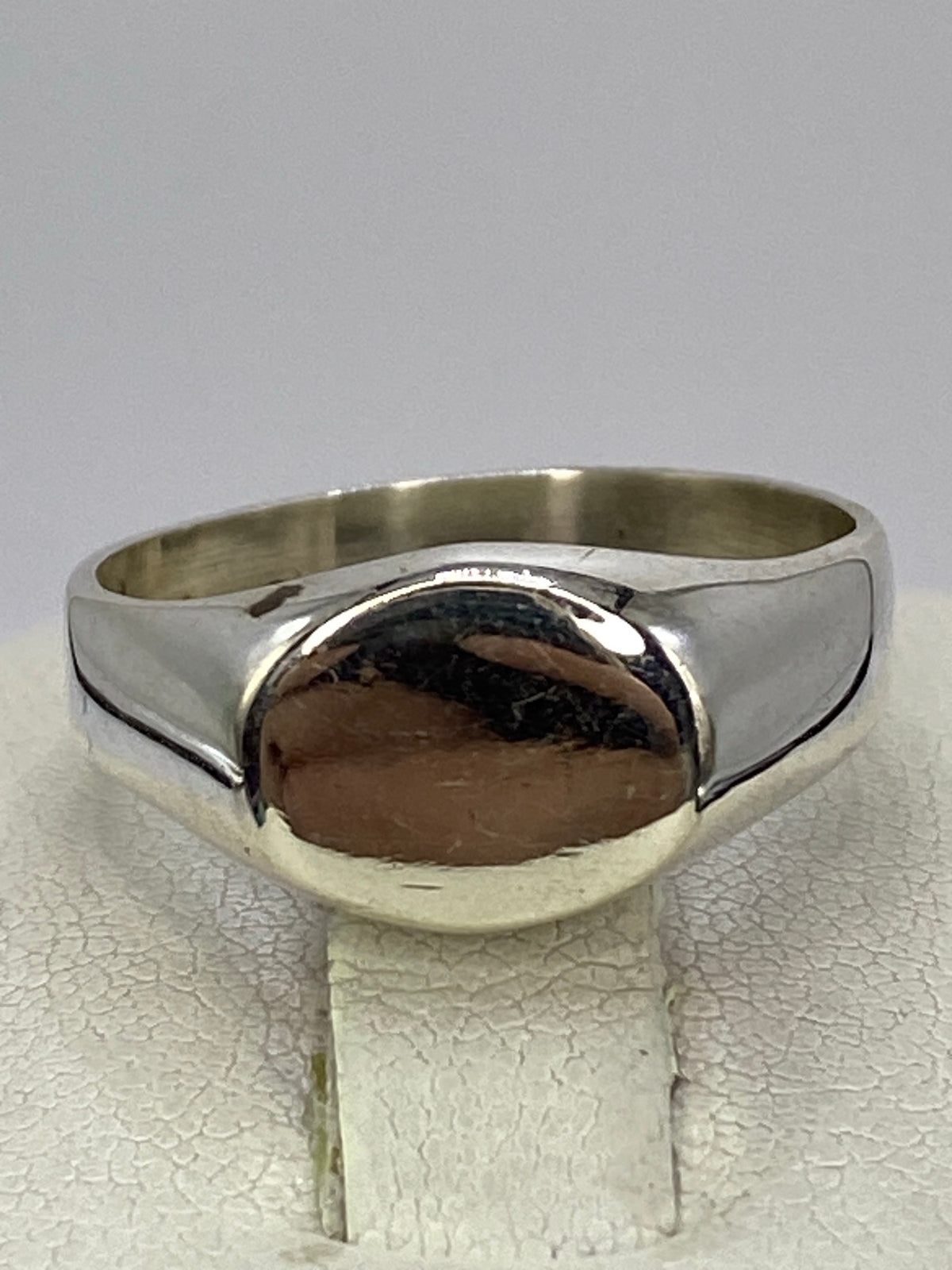 Anillo de plata calado pulido en la mano de una mujer, mostrando el brillo espejo de la banda