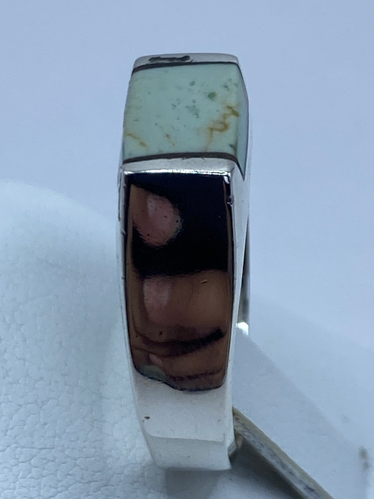 Anillo en la mano mostrando el acabado pulido y la turquesa en contexto de uso