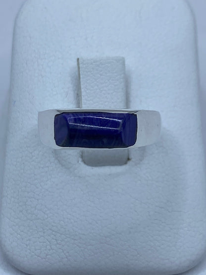 Anillo de plata con piedra morada engastada, vista superior sobre fondo blanco
