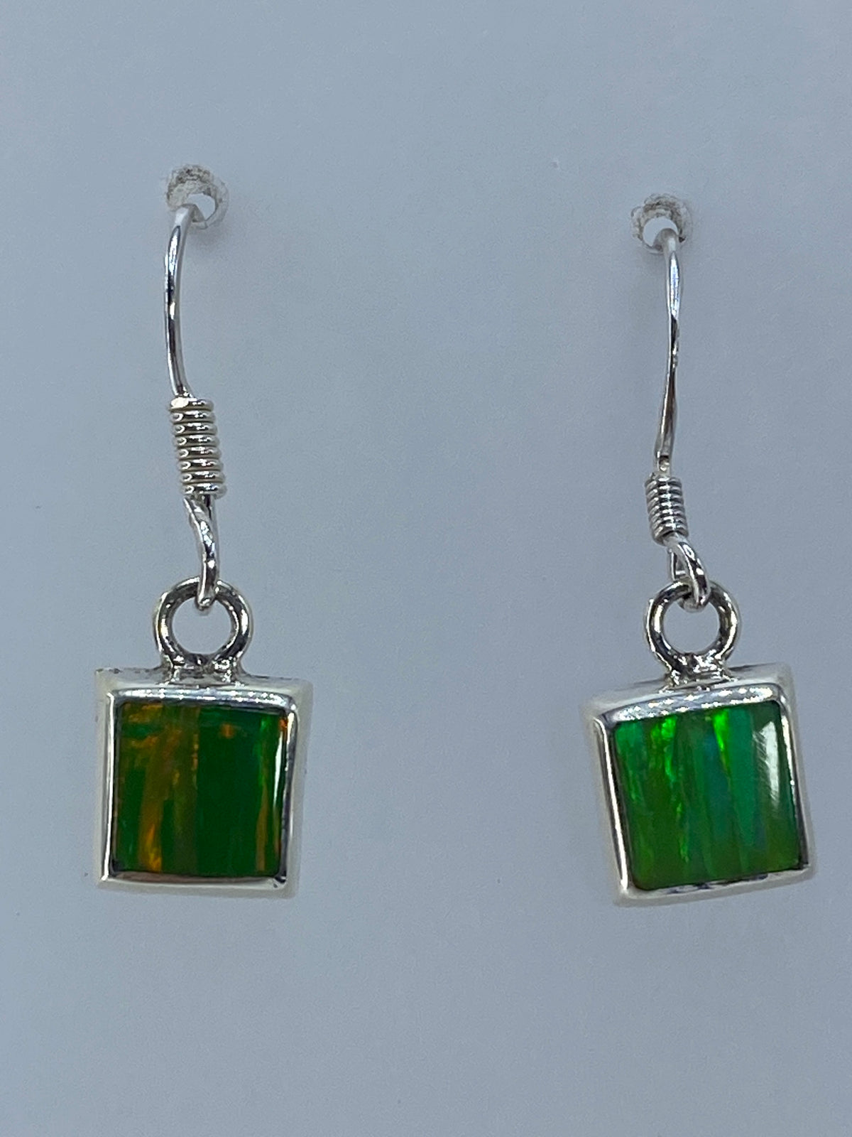 Par de aretes de plata 925 con ópalo de fuego verde limón, luz natural mostrando el brillo traslúcido