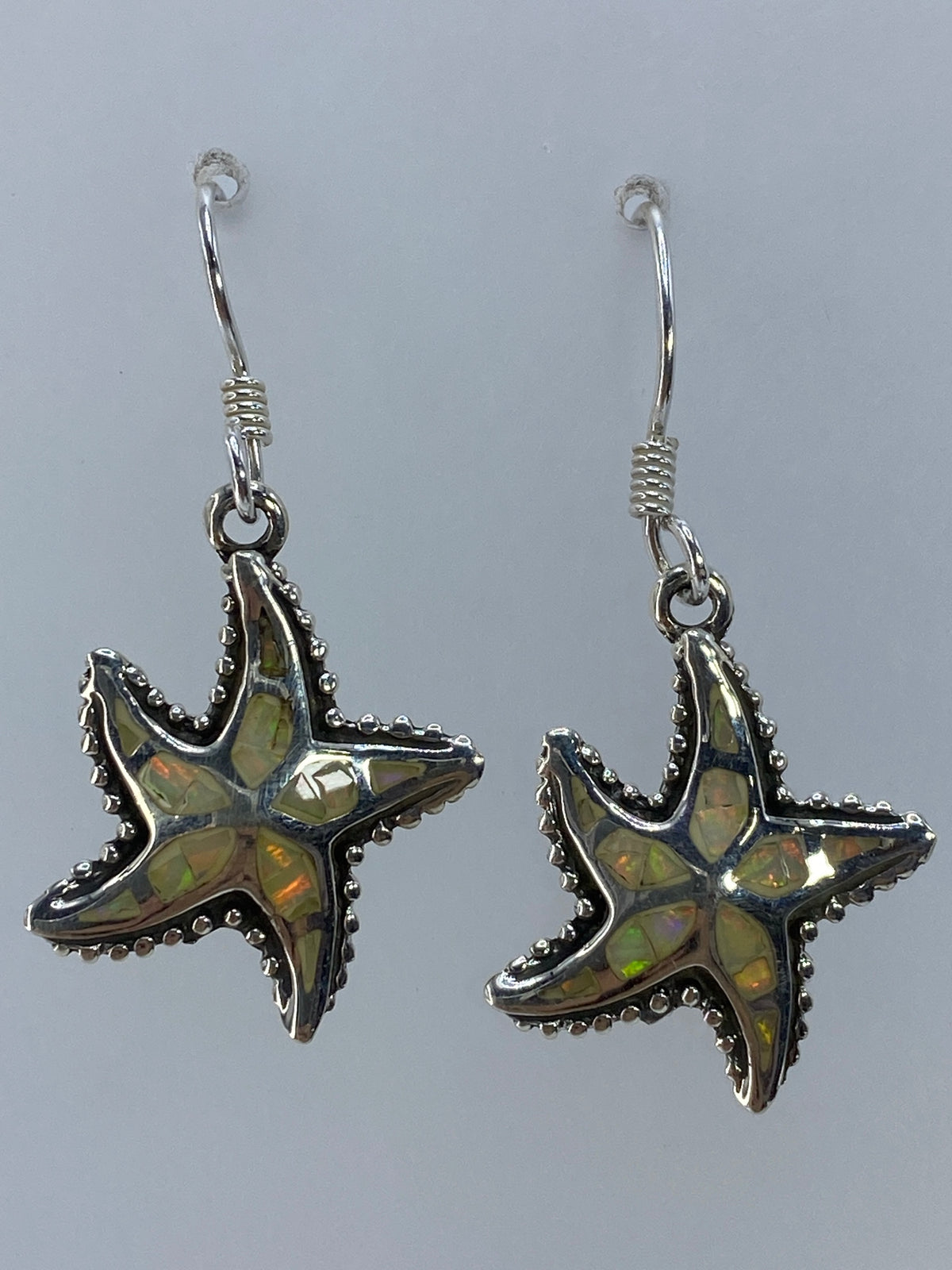 Aretes de estrella marina en plata 950 sobre fondo blanco mostrando el Quinto