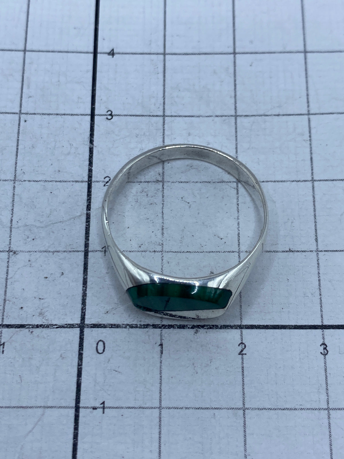 Anillo de malaquita sobre fondo gris mostrando el brillo de la plata pulida