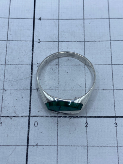 Anillo de malaquita sobre fondo gris mostrando el brillo de la plata pulida
