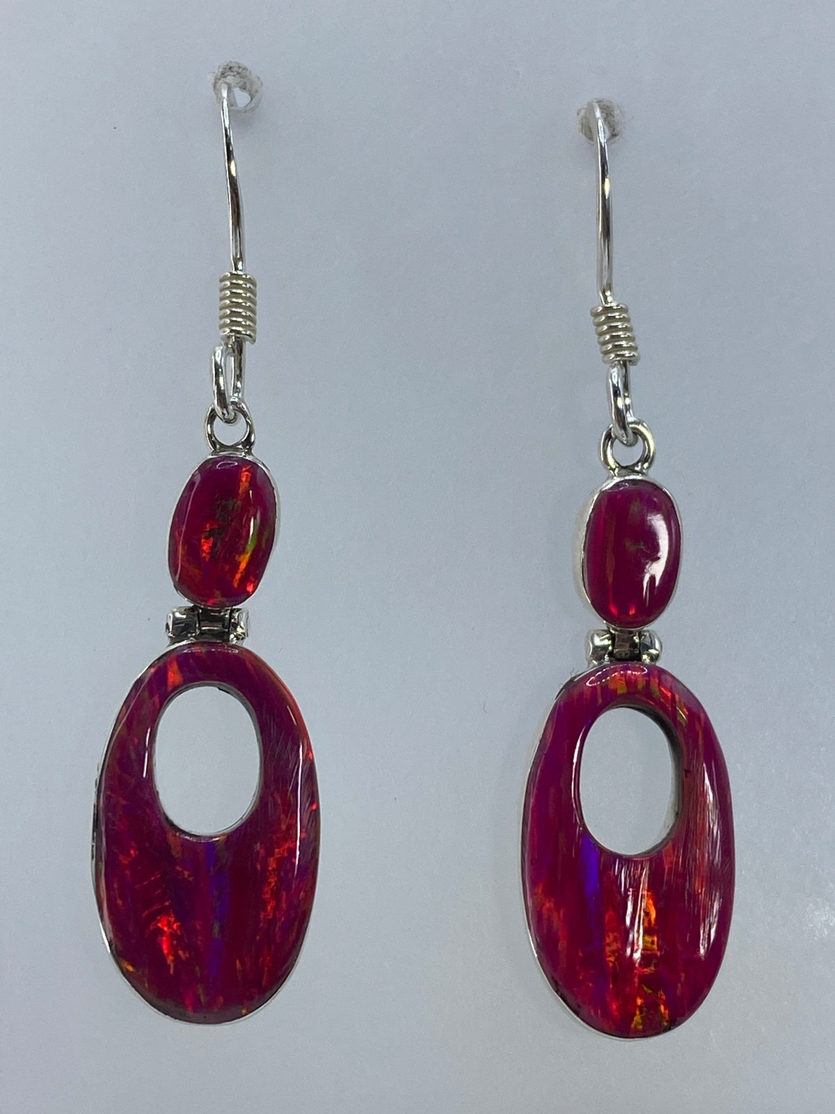 Detalle de cada arete mostrando los destellos rojos y naranjas del ópalo de fuego