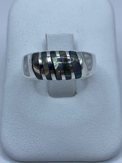 Anillo de plata 925 con concha de abulón iridiscente sobre dedo, tonos azul verdoso y púrpura