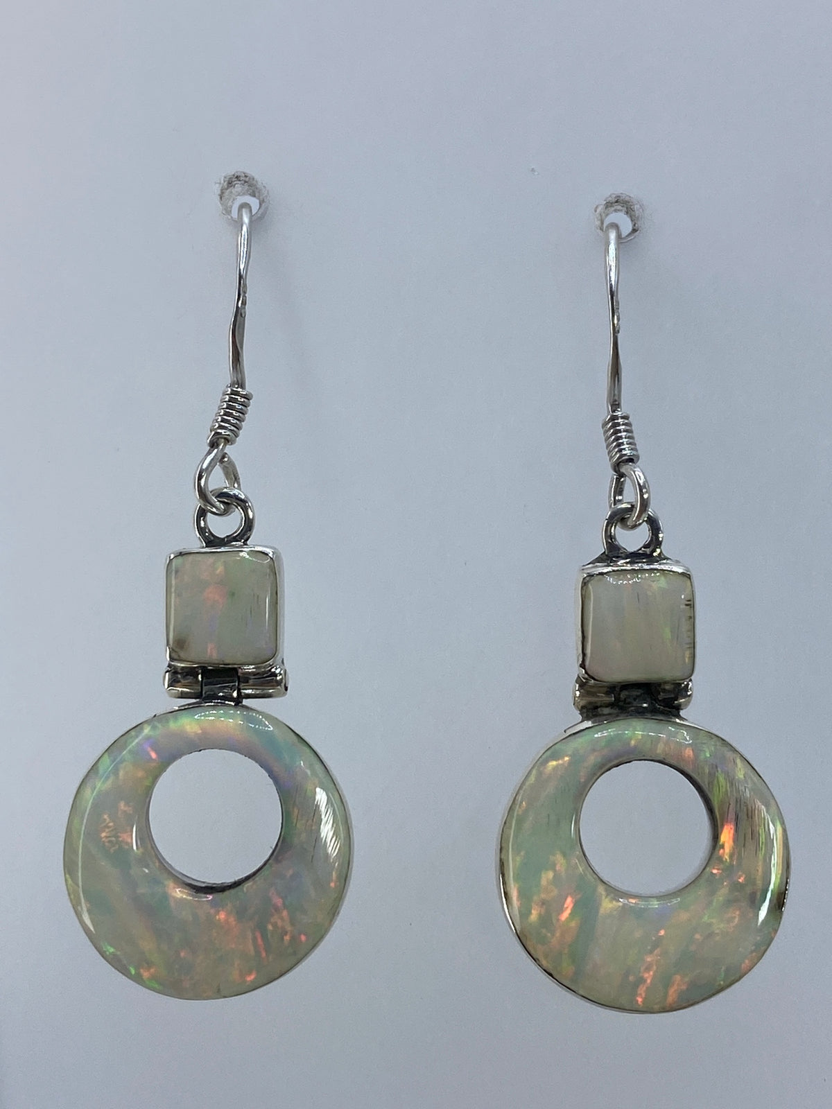 Par de aretes de plata 950 con ópalo de fuego multicolor colgando sobre fondo blanco