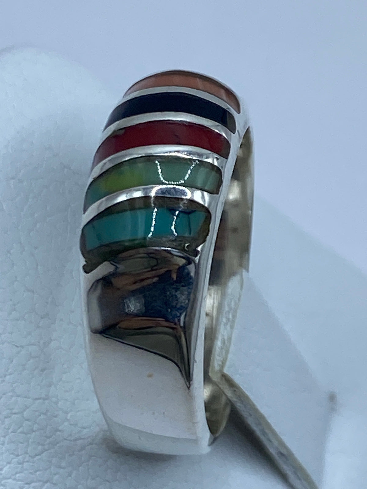Detalle de las tres piedras: turquesa, coral y ónix en el anillo de plata