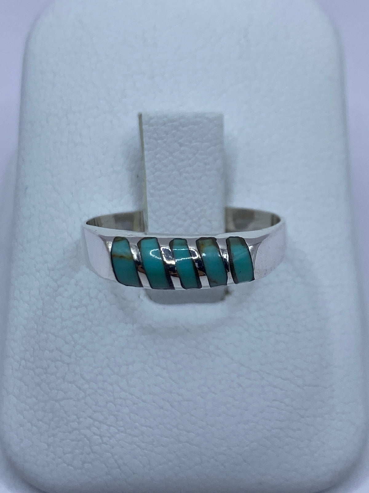 Anillo de plata con turquesa azul cielo engastada a mano, en dedos sobre fondo blanco