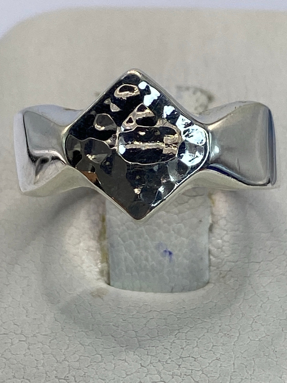 Anillo de plata repujado en forma de V sobre fondo blanco