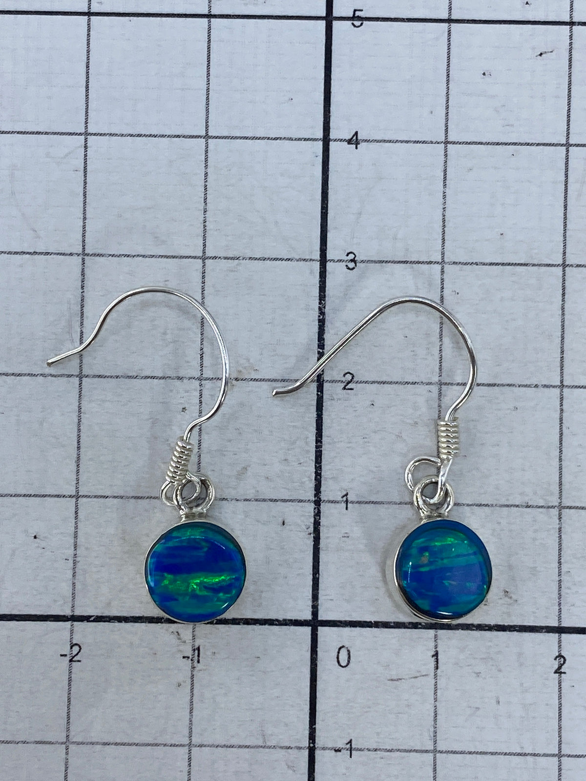 Aretes en balanza digital mostrando peso de 1.42 gramos para el par