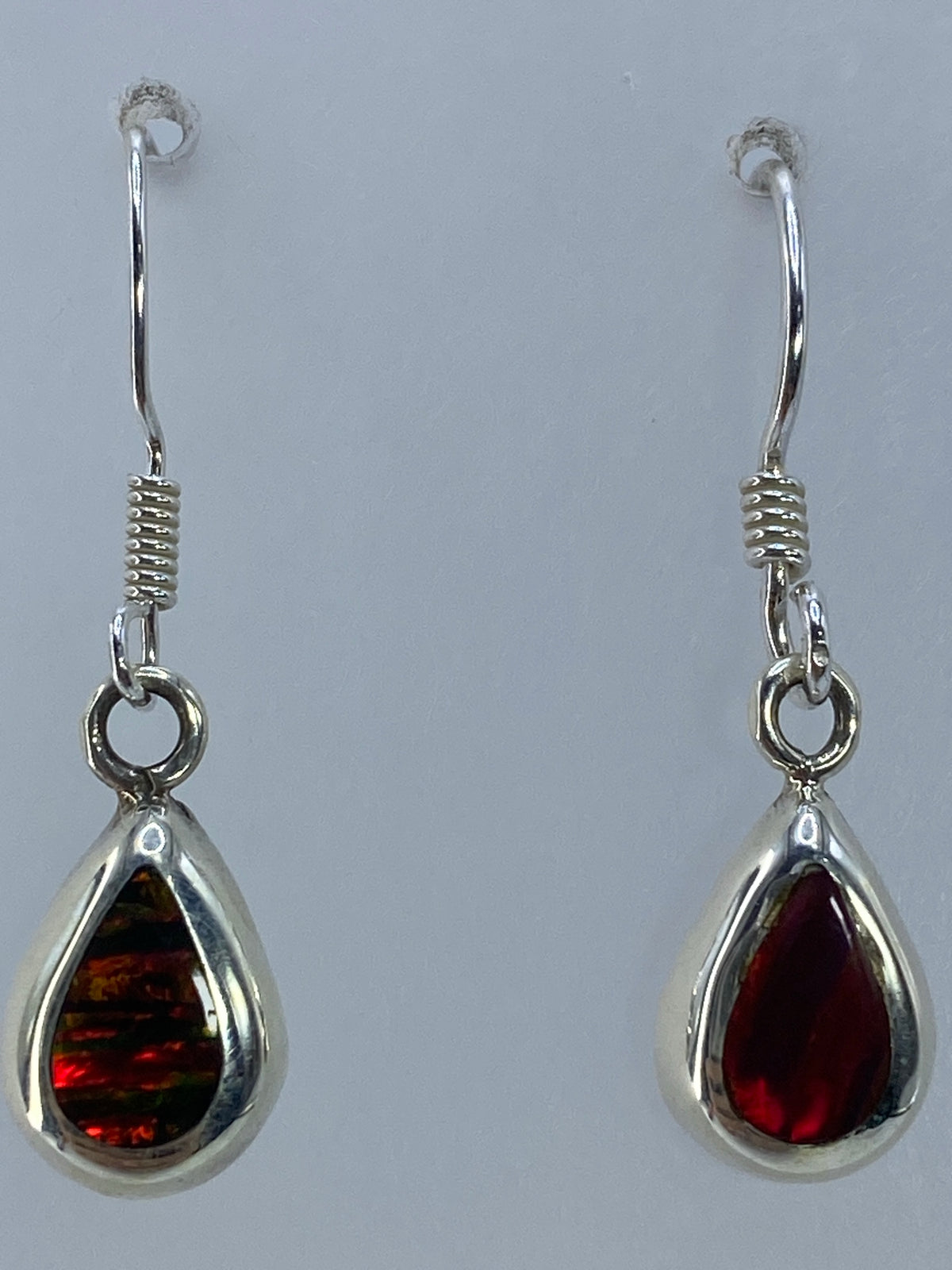 Aretes de ópalo fuego sobre fondo blanco mostrando el Quinto 925