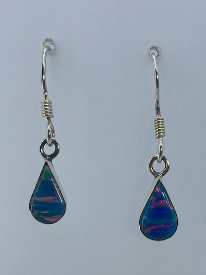 Par de aretes de plata con ópalo de fuego multicolor, mostrando el juego de colores naranja, azul y verde