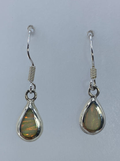 Par de aretes de plata con ópalo de fuego multicolor colgando, vista frontal
