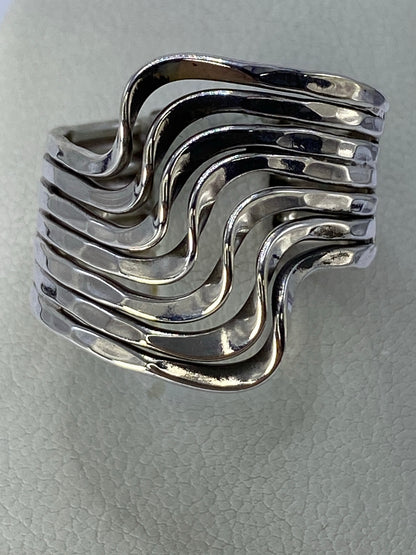 Anillo de plata cartoneado en capas fluidas en mano de mujer