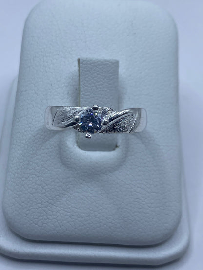 Anillo de plata solitario con circonia blanca brillante en mano de mujer