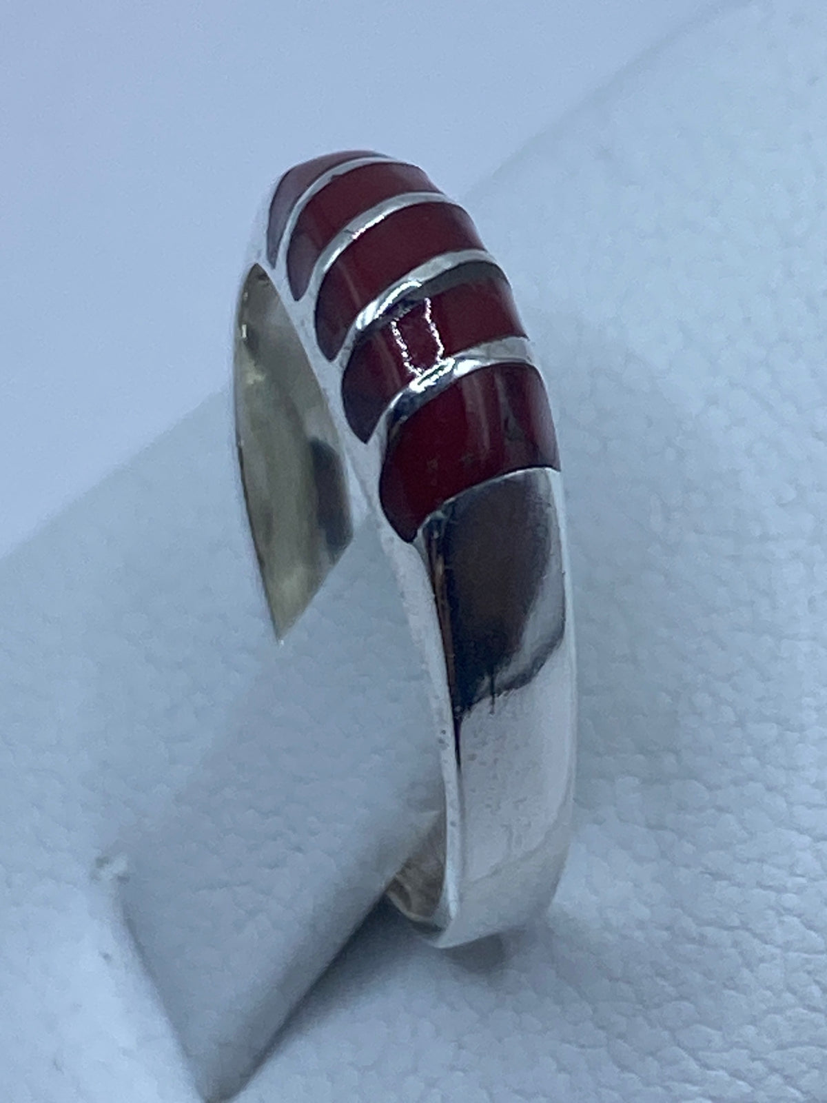 Detalle del coral rojo brillante flanqueado por bandas de plata en Taxco