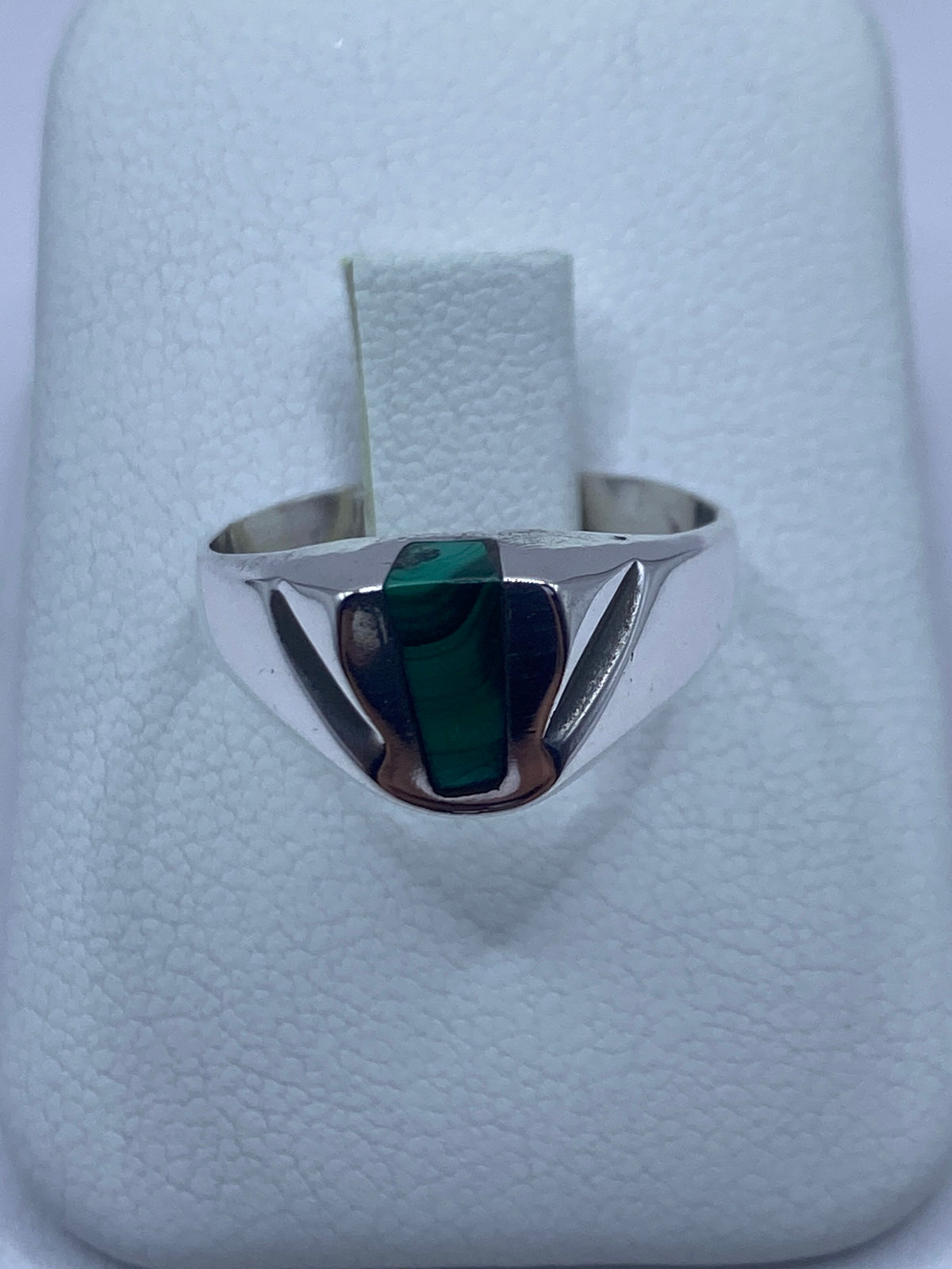 Anillo de plata con malaquita verde rectangular en la mano de una persona