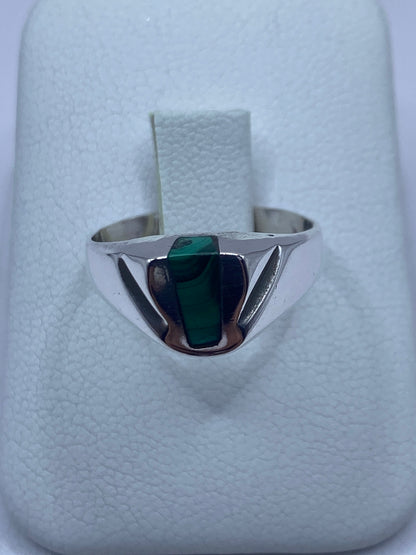 Anillo de plata con malaquita verde rectangular en la mano de una persona