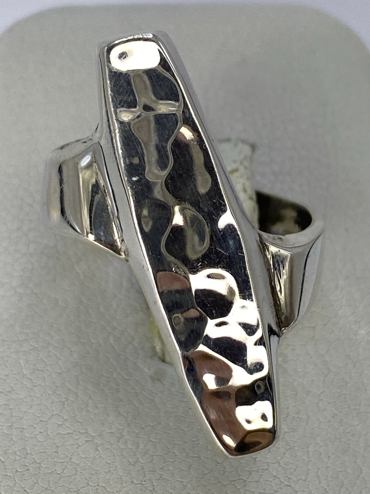 Anillo de plata repujado en la mano de una mujer, textura en relieve visible