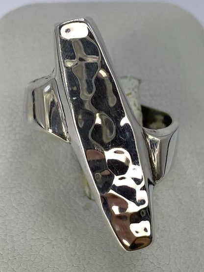 Anillo de plata repujado en la mano de una mujer, textura en relieve visible