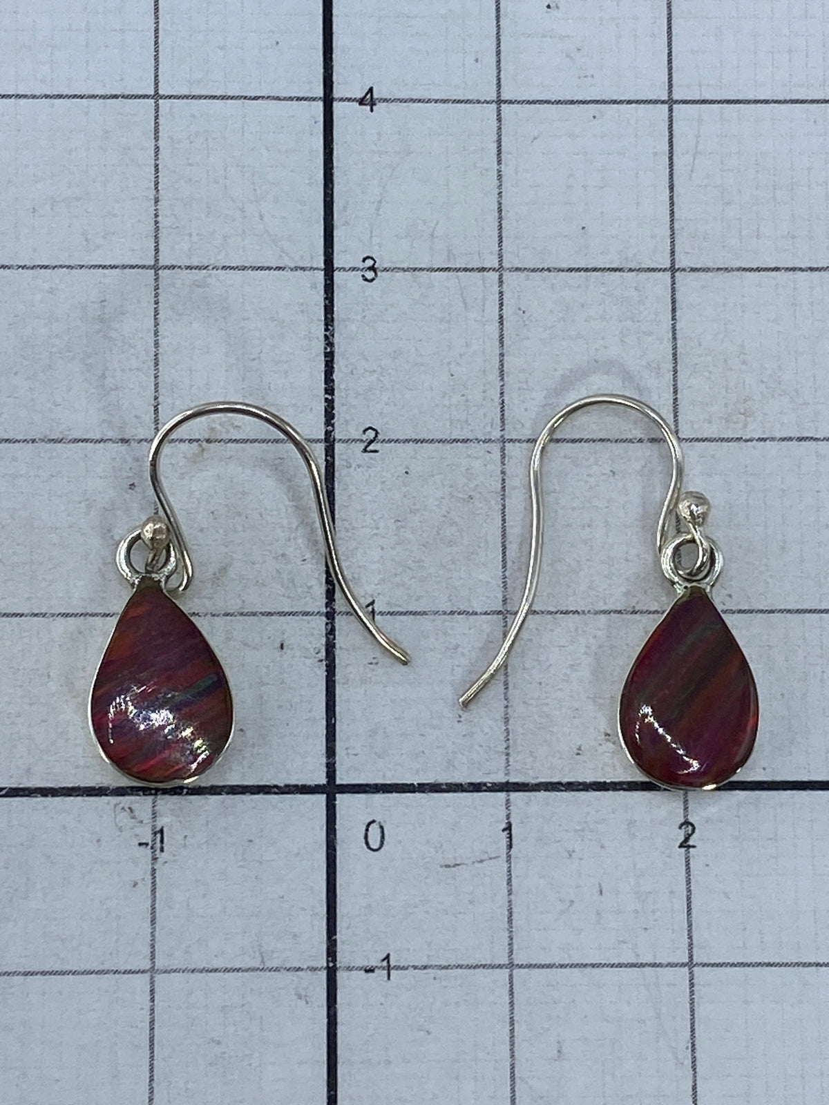 Aretes de ópalo de fuego sobre fondo blanco, capturando los reflejos del mineral
