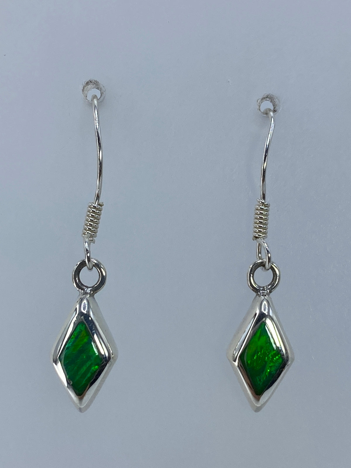 Detalle de los aretes mostrando el color verde limón y los destellos del ópalo