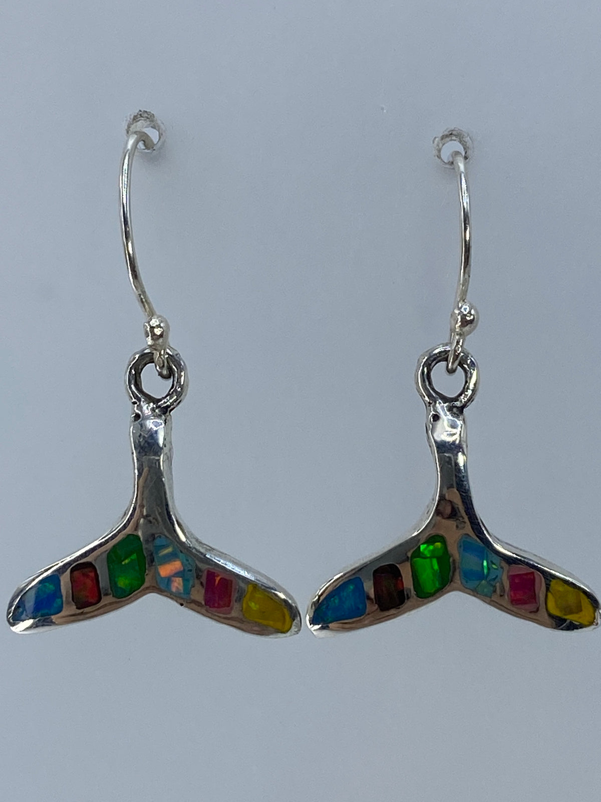 Aretes ópalo de fuego mostrando destellos de color rojo, verde y azul