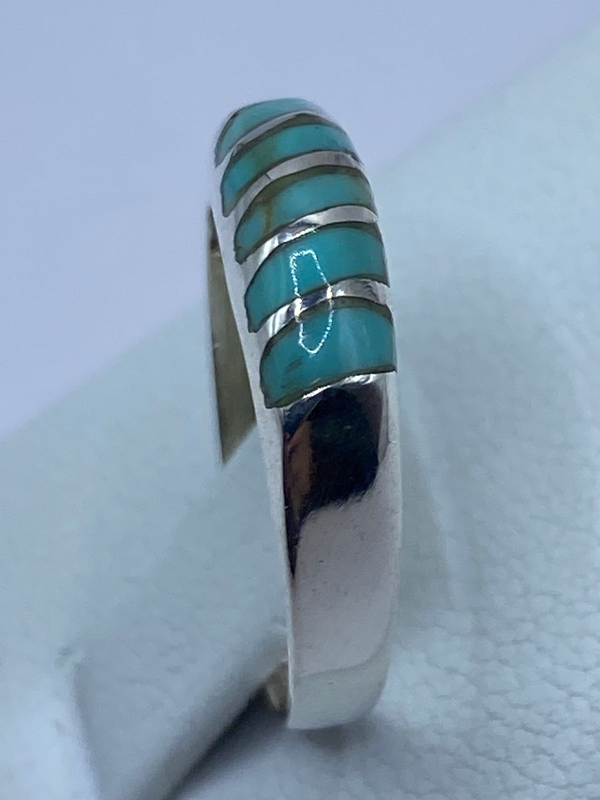 Anillo puesto en la mano, mostrando el diseño minimalista con turquesa
