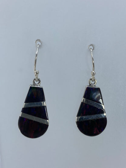 Detalle del engaste a mano del ópalo multicolor en plata 950, mostrando los tonos ámbar y naranja