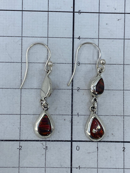 Aretes puestos, largo 3.9 cm, contra fondo claro mostrando la transparencia del ópalo