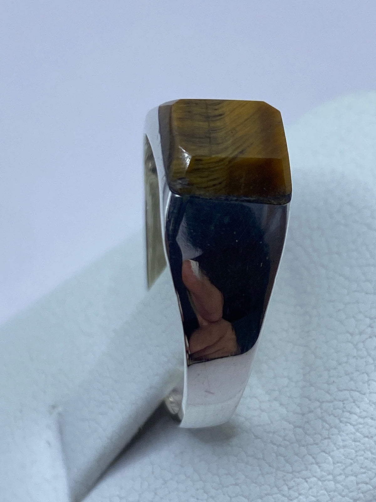 Anillo solitario de Ojo de Tigre puesto en dedo, mostrando reflejo luminoso