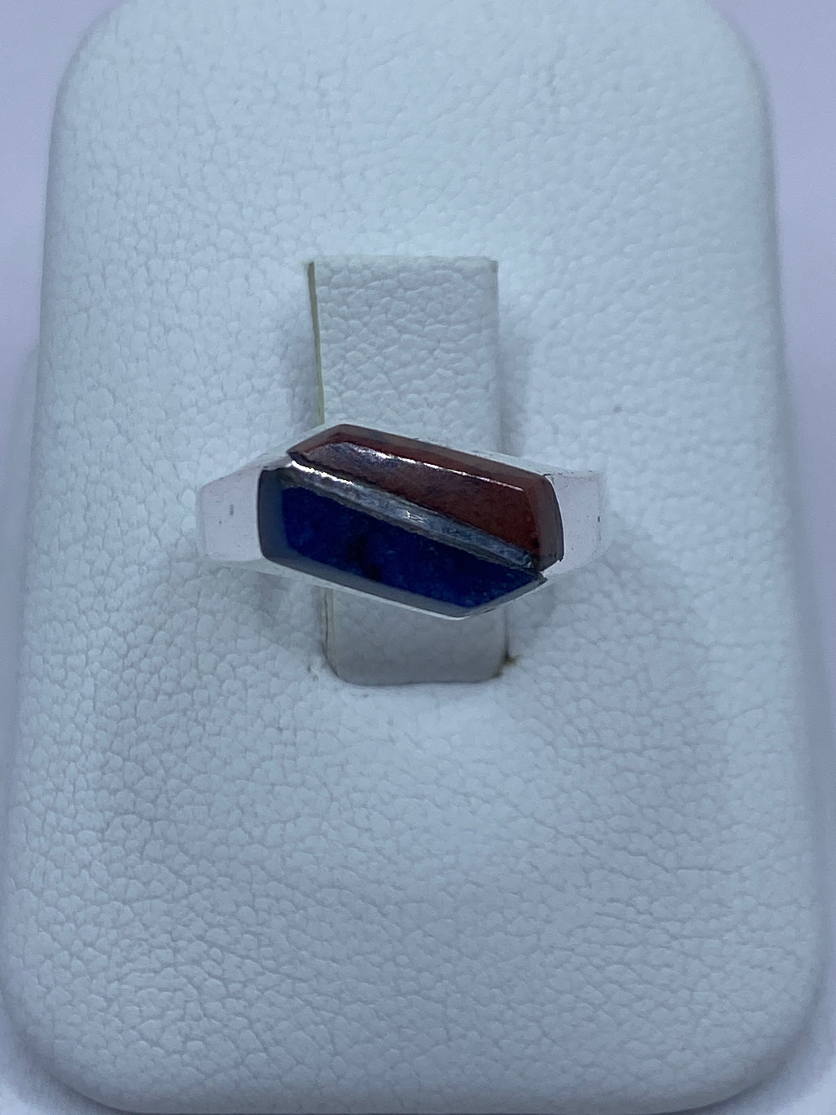 Anillo de plata 925 con lapislázuli azul engastado a mano, visto de frente sobre algodón blanco