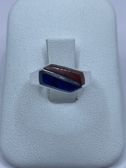 Anillo de plata 925 con lapislázuli azul engastado a mano, visto de frente sobre algodón blanco