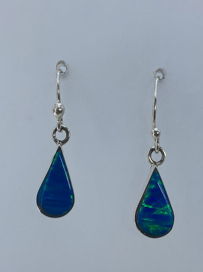Detalle del ópalo de fuego con reflejos verdes en gancho de plata pulida