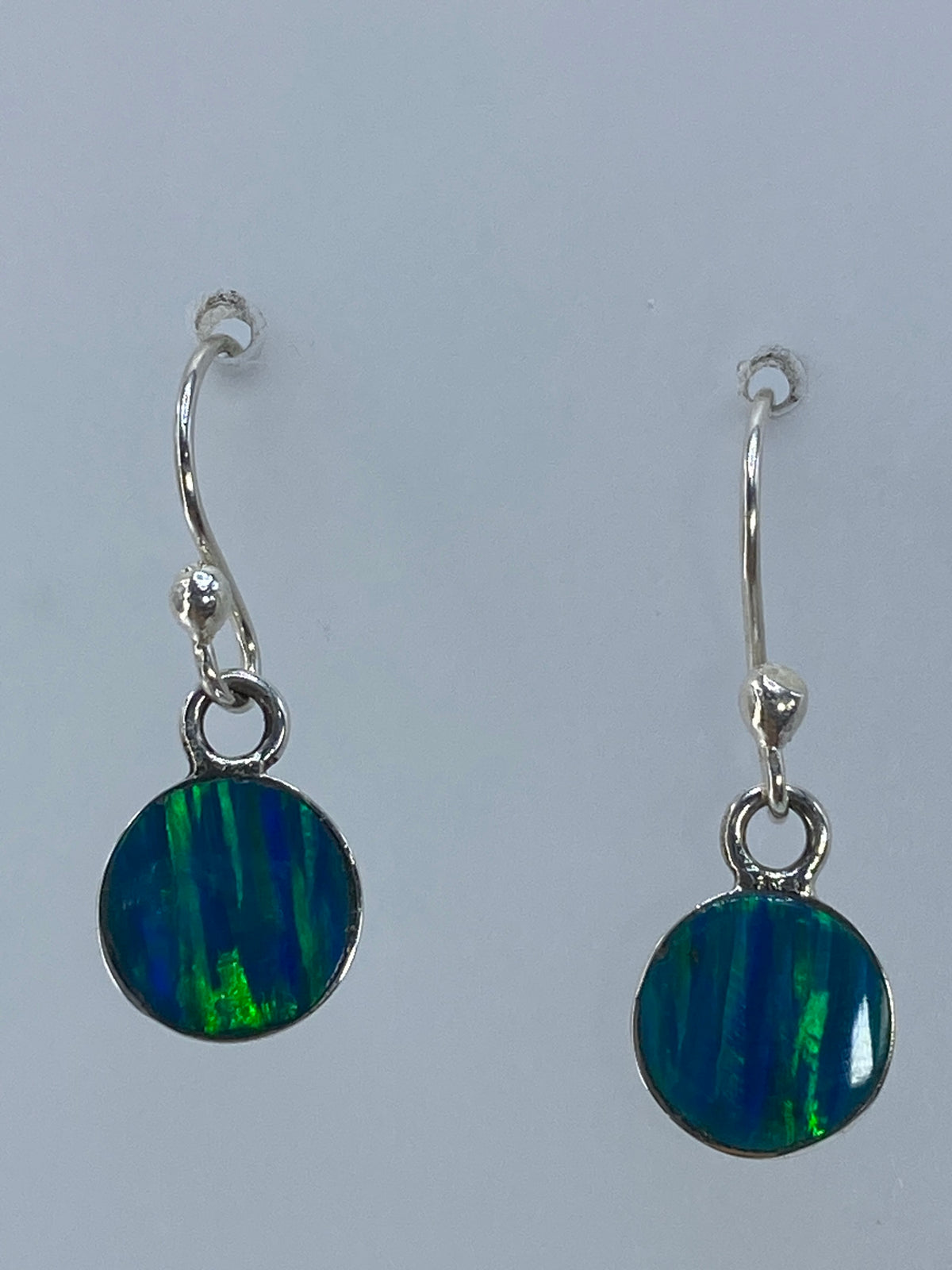 Par de aretes de plata con ópalo de fuego verde limón brillando al natural