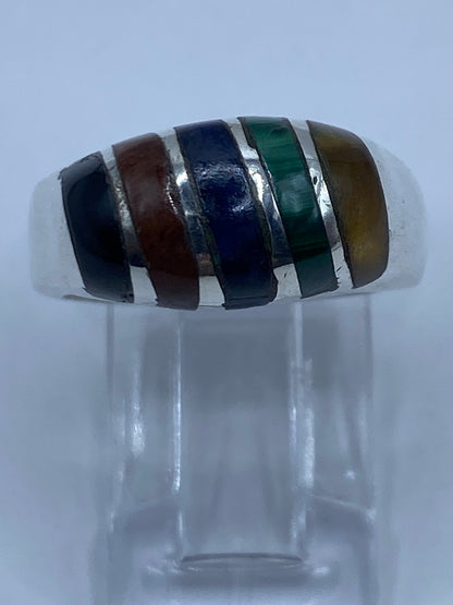 Anillo multicolor llevado en dedo, mostrando el equilibrio de las cuatro piedras