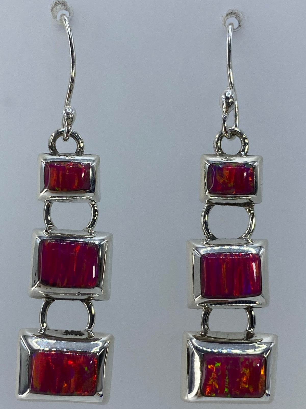 Aretes puestos en las orejas mostrando el brillo rosa del ópalo de fuego