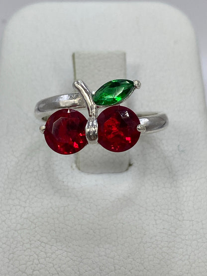 Anillo de plata 925 con dos circonia rojas brillantes en forma de cereza sobre fondo blanco