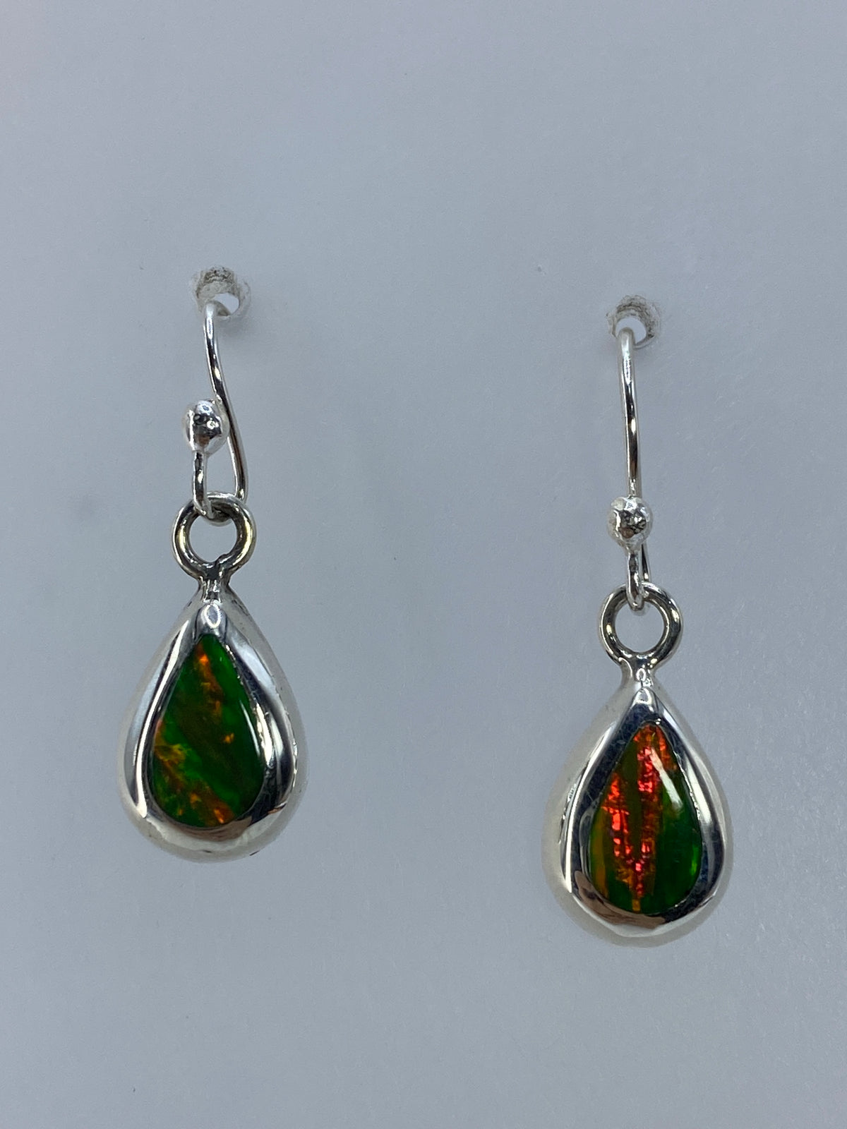 Detalle de un arete mostrando el color naranja del ópalo de fuego y el engaste de plata 925