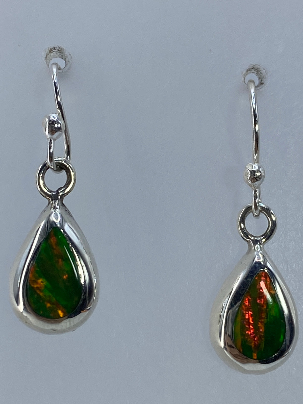 Los dos aretes colgando juntos, destacando el brillo del ópalo