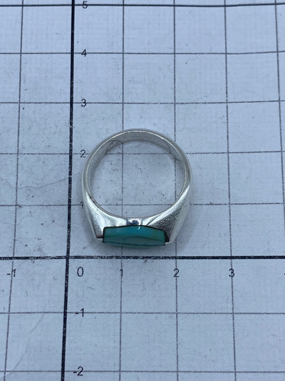 Anillo puesto en dedo mostrando el brillo natural de la turquesa y el acabado satinado de la plata