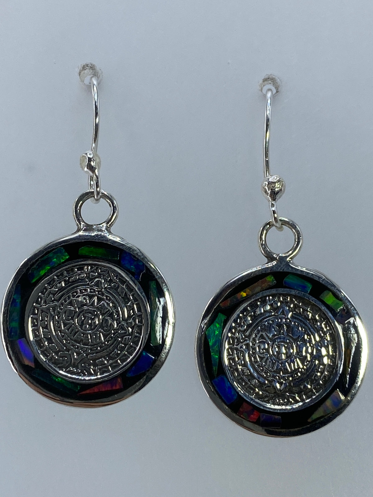 Aretes de plata pura con incrustación de piedra ópalo de fuego sobre fondo blanco