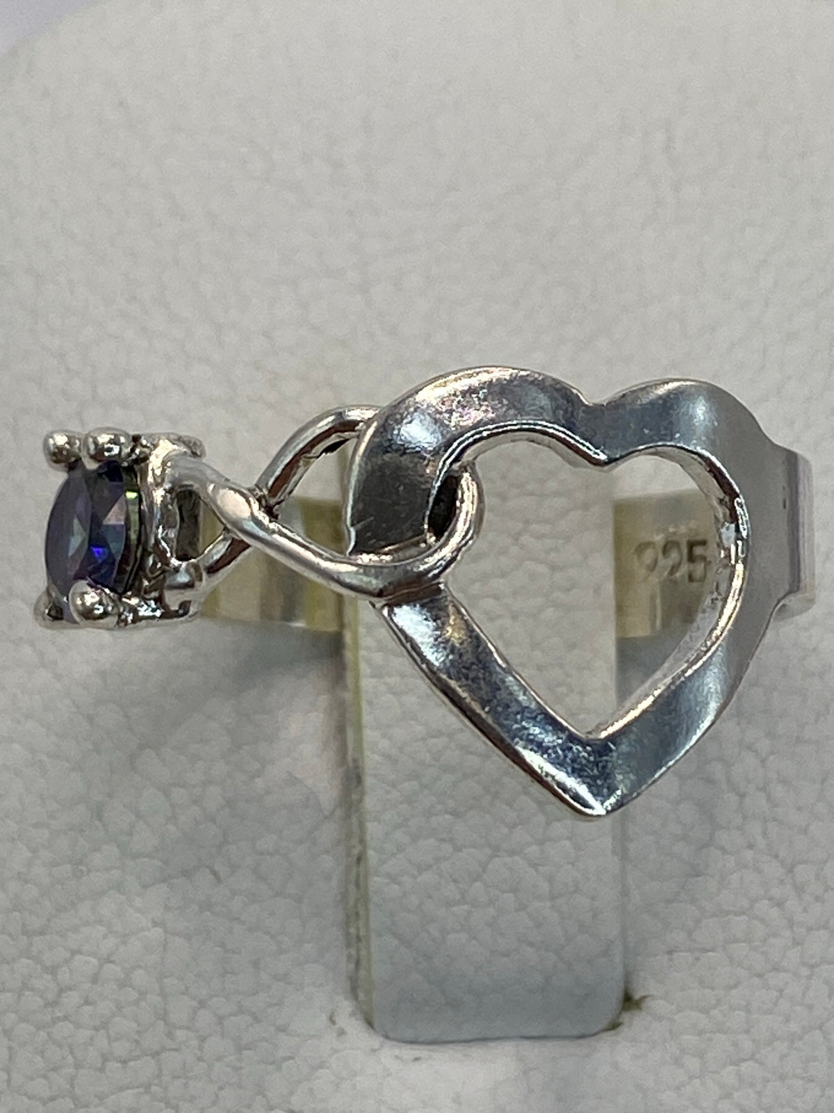 Anillo de plata 925 con circonia multicolor en solitario, sobre mano con fondo neutro